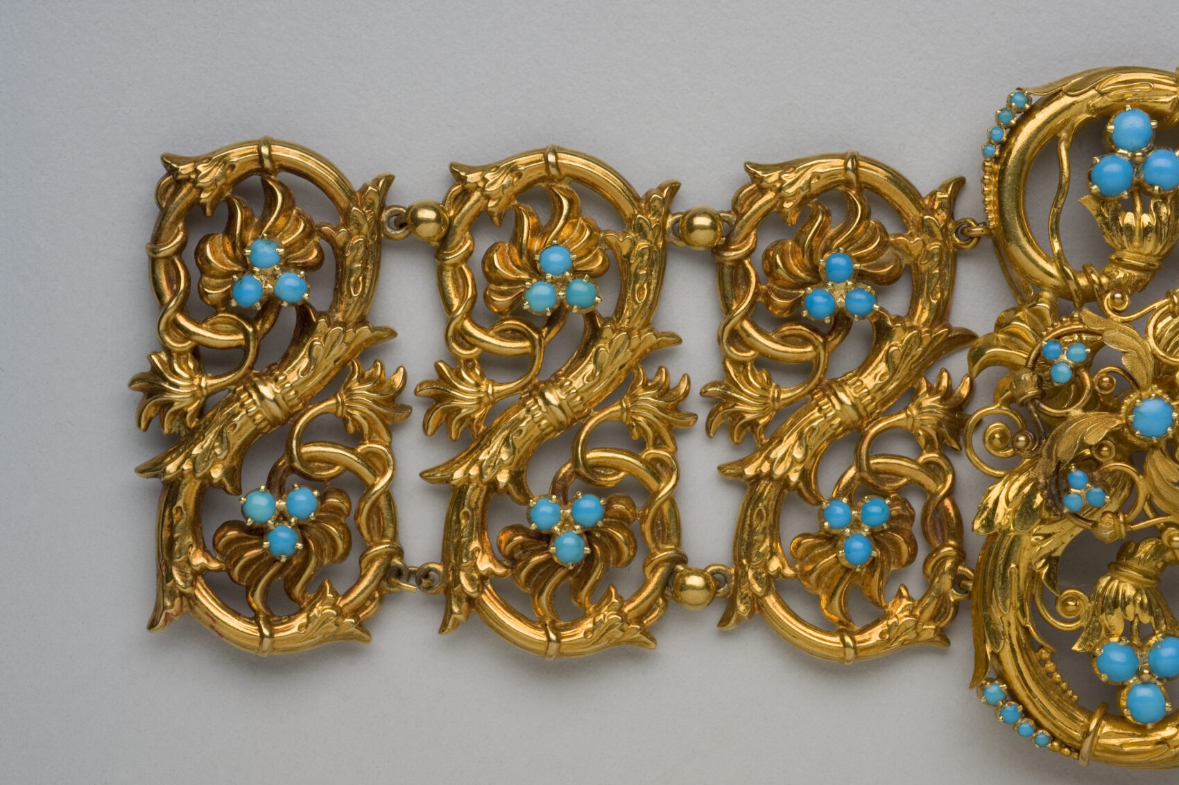 Zlatý ornamentální náramek s modrými kamínky