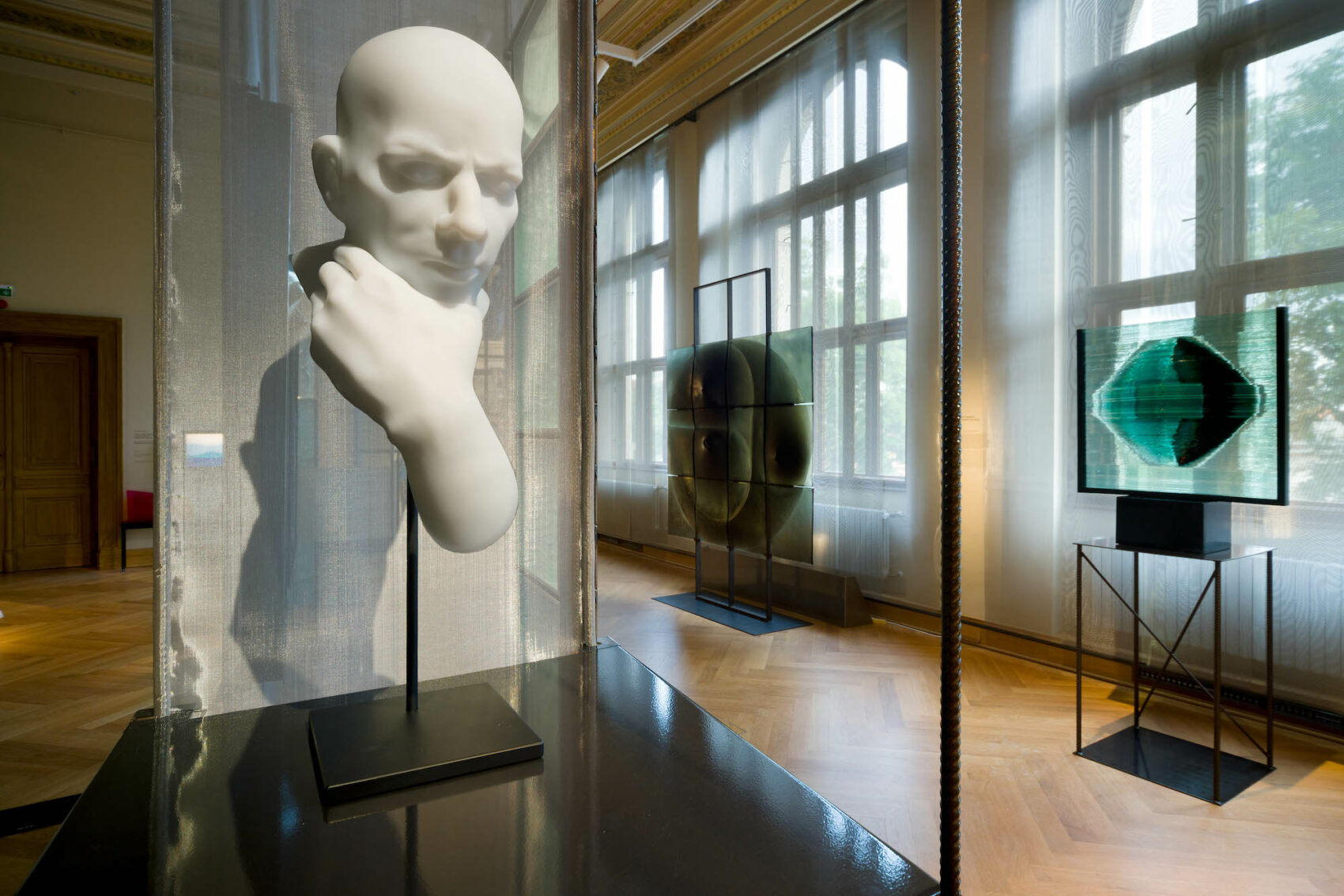 Pohled do výstavy skleněných plastik, v popředí hlava z bílého skla